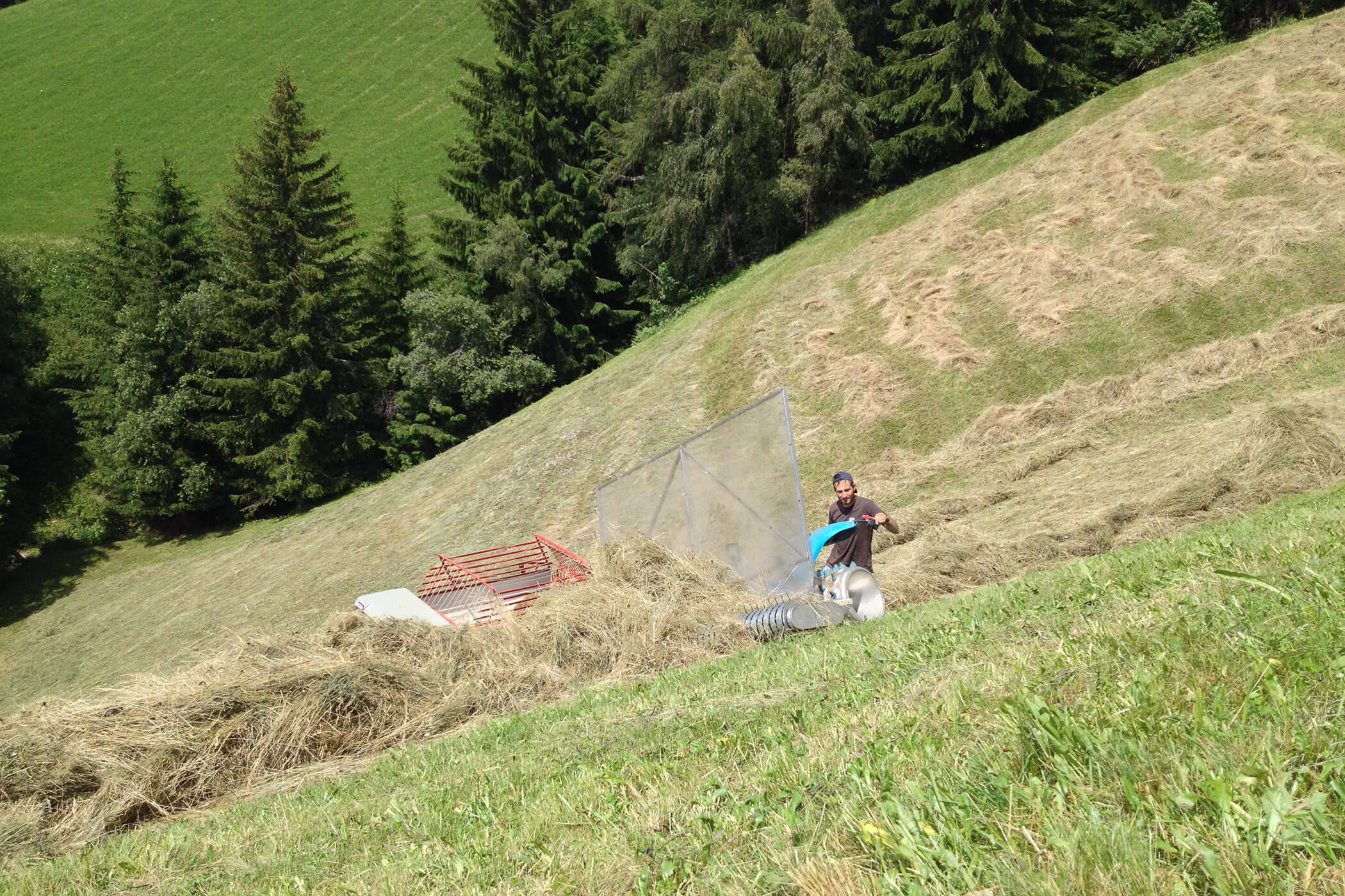 Bauer schiebt das Heu mit einer Maschine weiter - Scheaterhof