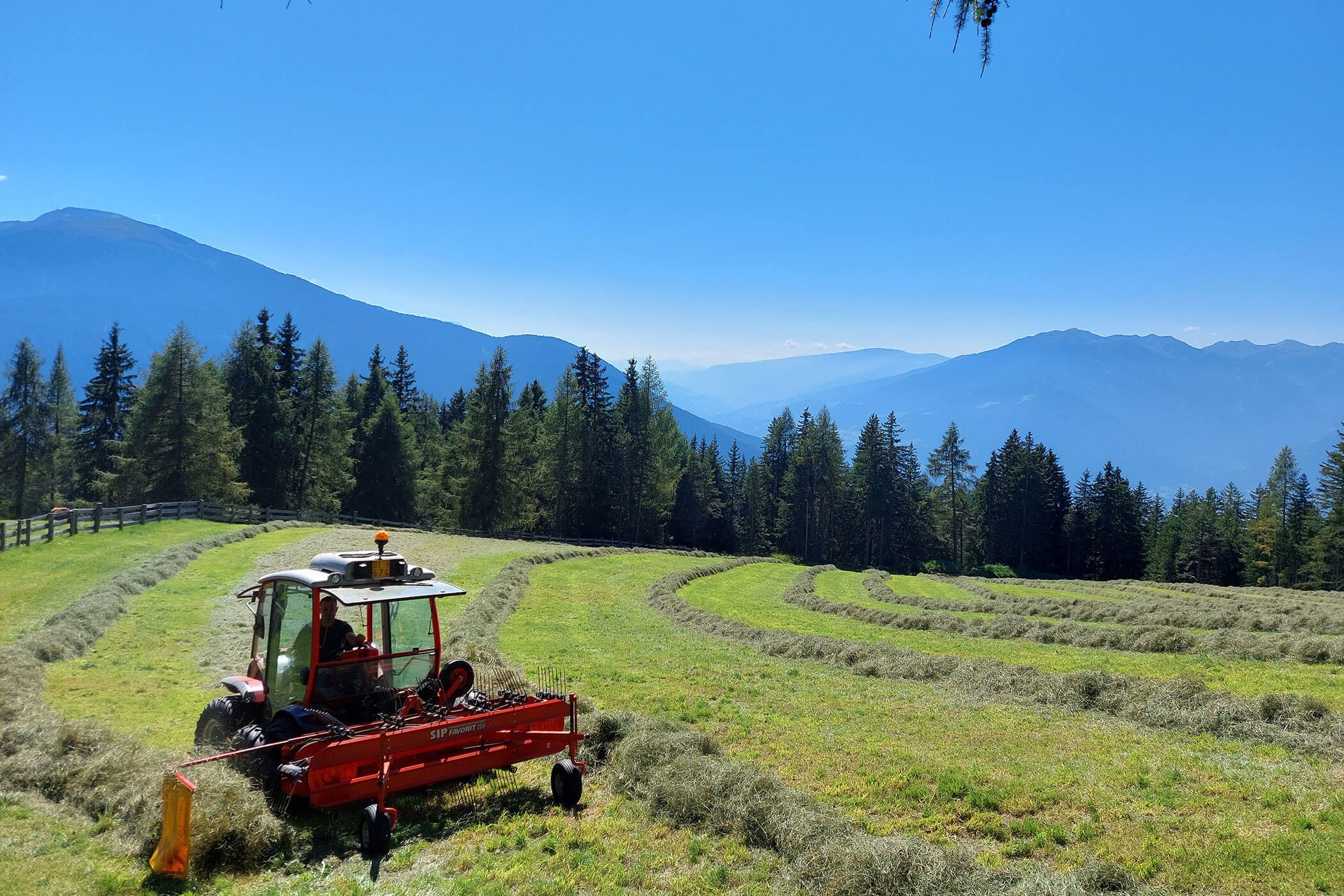 Bauer mit seinem Traktor bei der Heuarbeit auf dem Feld - Scheaterhof