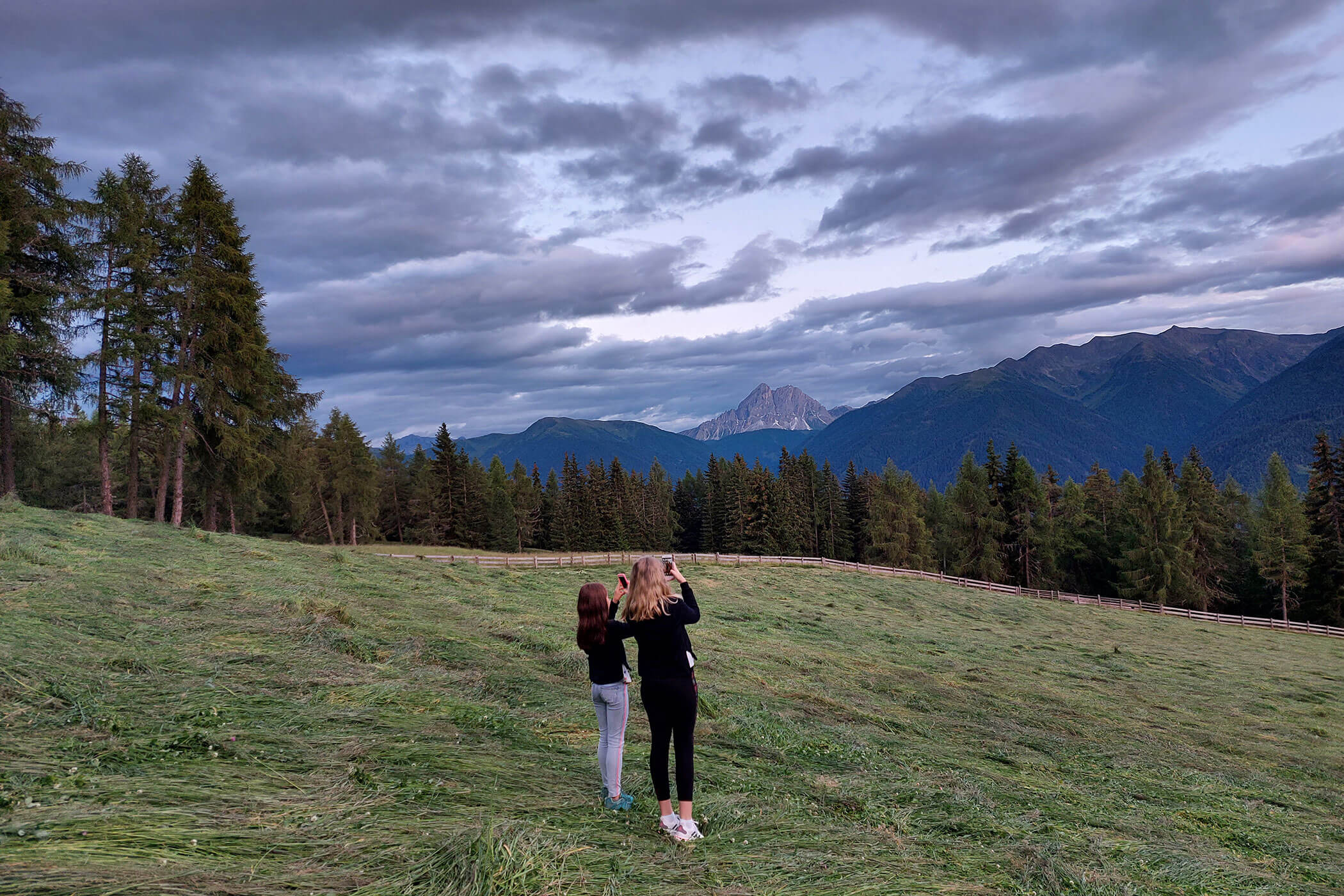 Zwei Kinder fotografieren die Berglandschaft inmitten der Wiesen - Scheaterhof