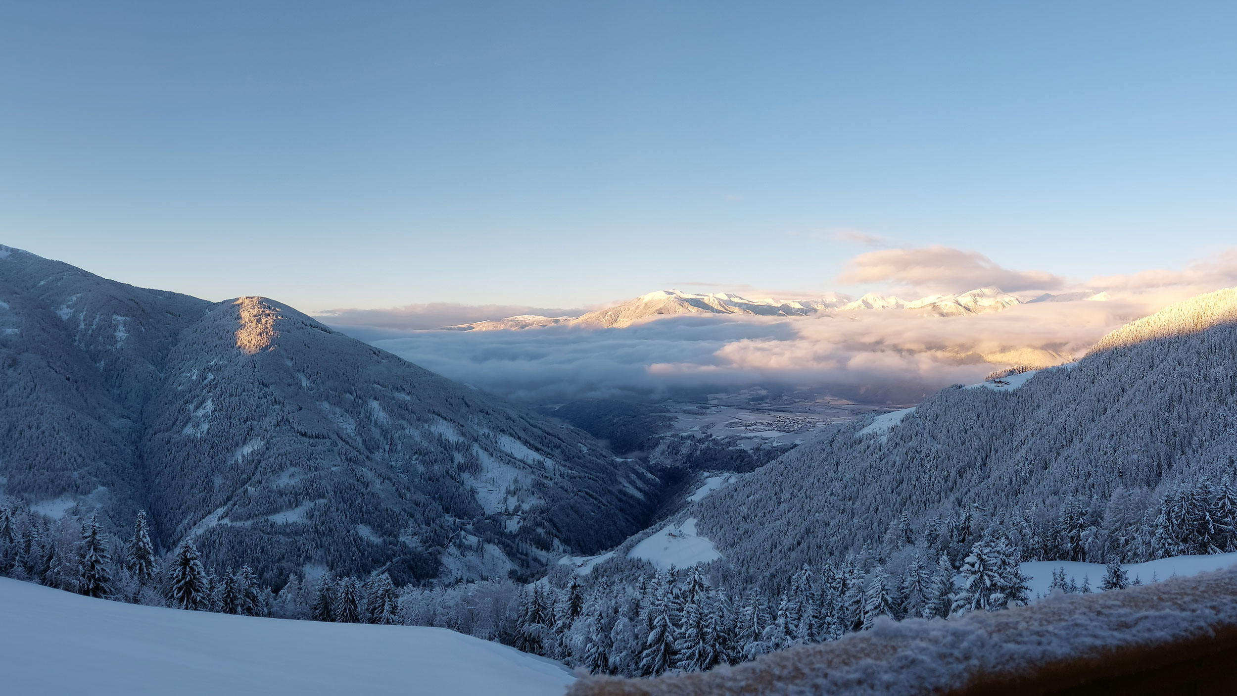 Ausblick vom Scheaterhof auf die winterliche Landschaft mit verschneiten Bergen und Bäumen