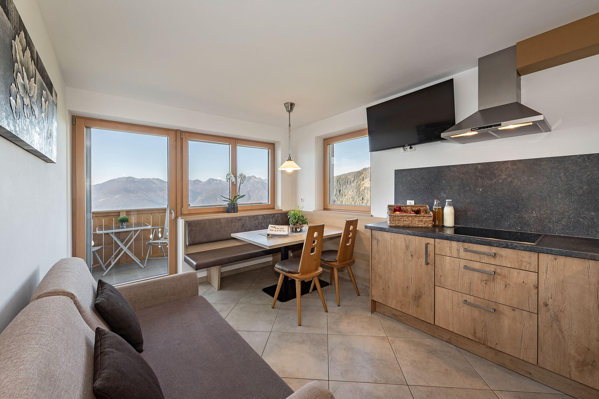 Wohnküche in der Ferienwohnung Panorama mit Kochnische, Esstisch, Sofa und TV - Scheaterhof