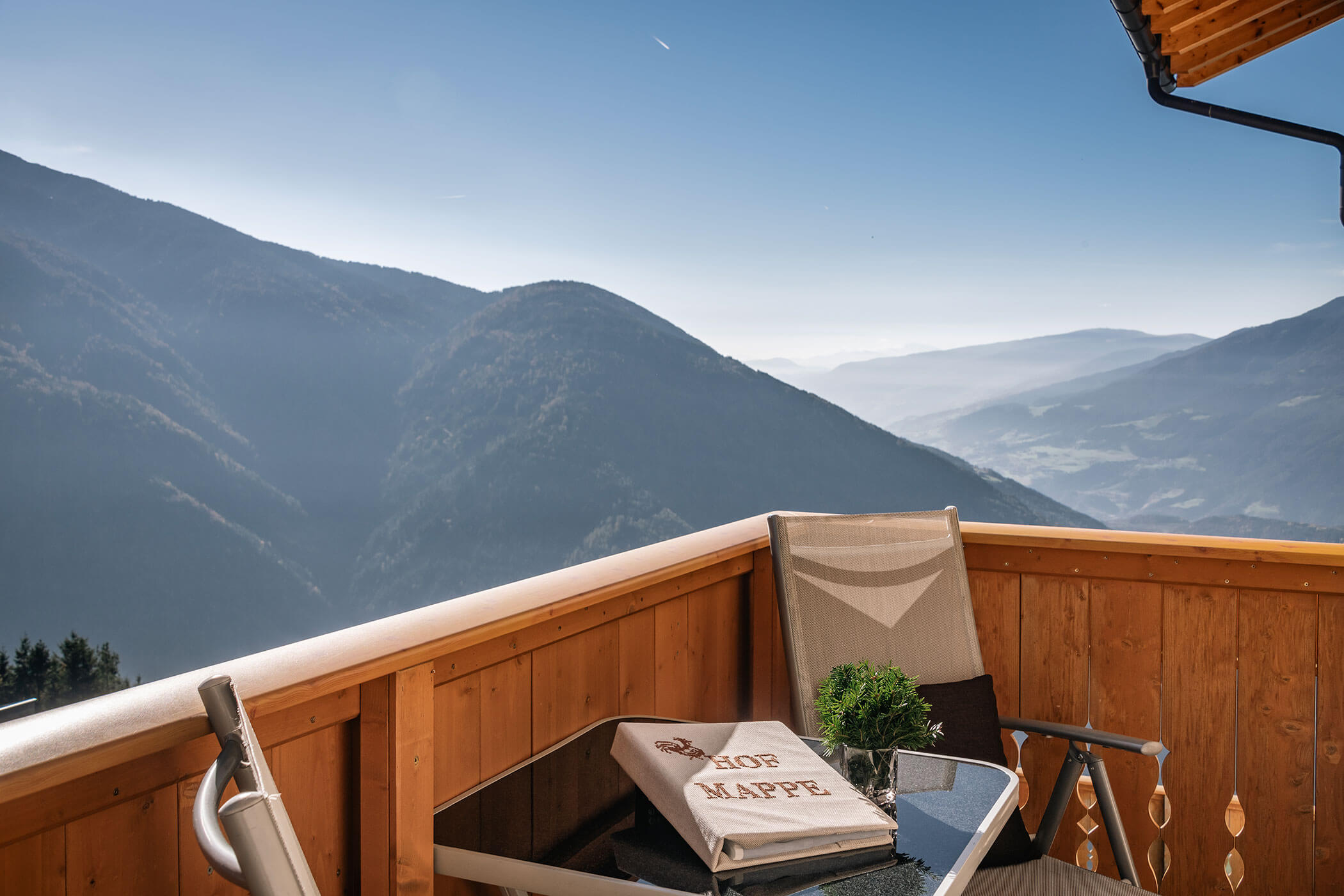 Balkon von der Ferienwohnung Peitlerkofel mit Tisch, Stuhl und Aussicht auf Tal und Berge - Scheaterhof