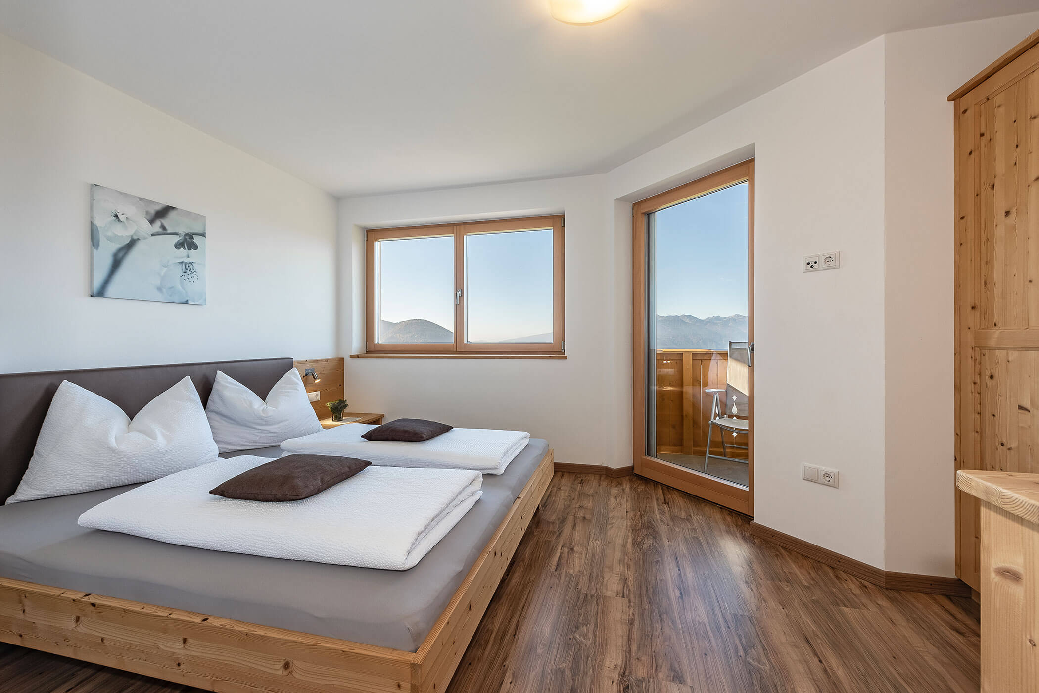 Schlafzimmer in der Ferienwohnung Plose mit Doppelbett und Blick auf den Balkon - Scheaterhof